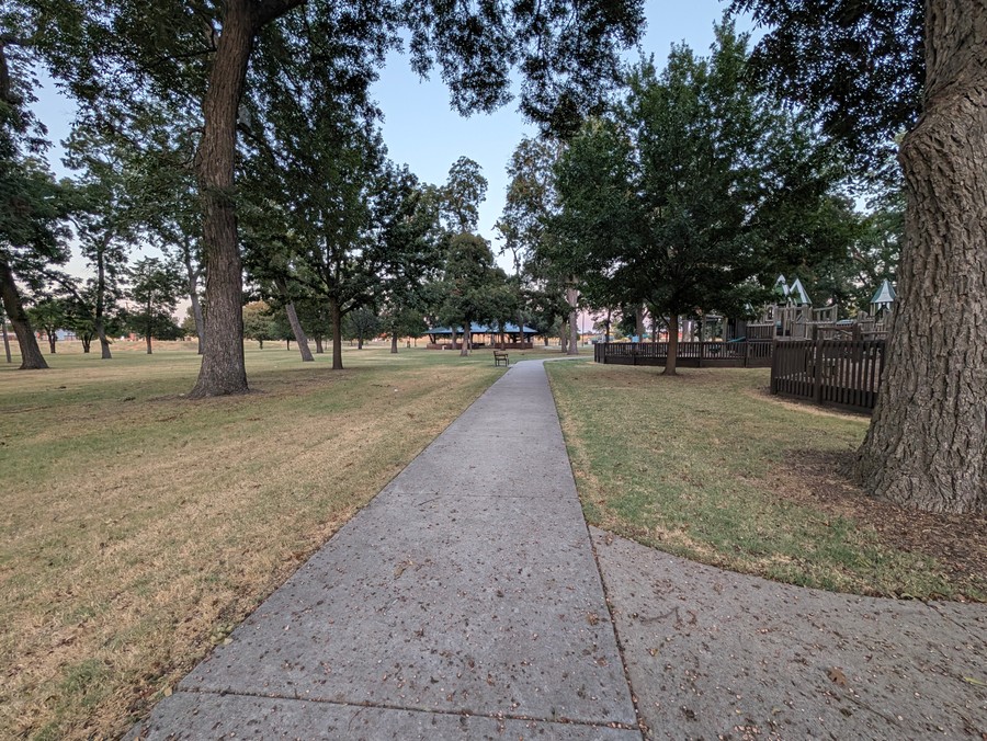 Paved walking path through the trees at Leonard Park.