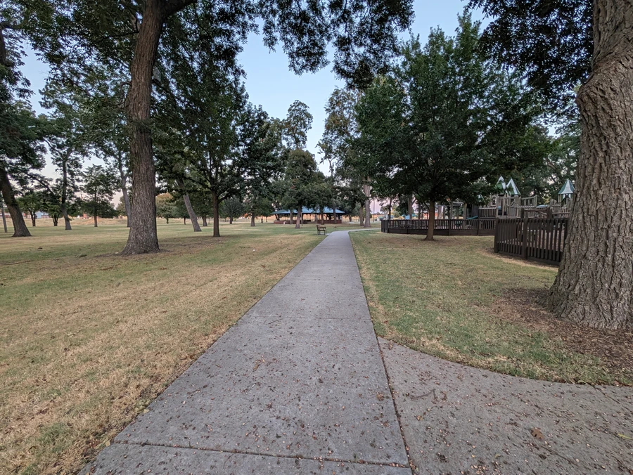 Paved walking path through the trees at Leonard Park.