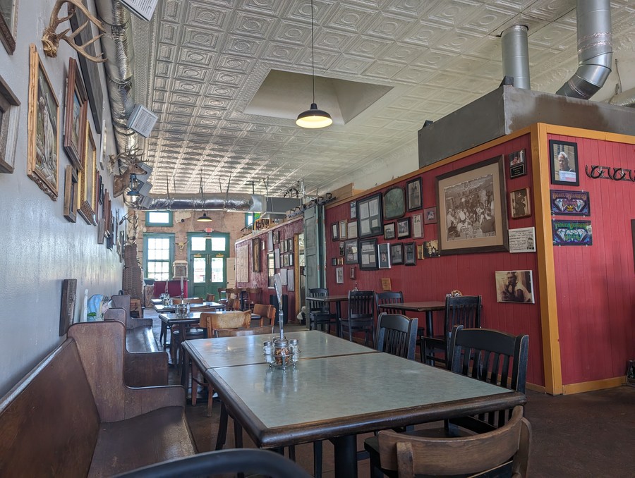 The pressed-tin ceiling and family photos in the dining room at St. Joe's Pizza, June 2024.