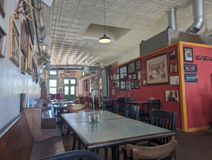 The pressed-tin ceiling and family photos in the dining room at St. Joe's Pizza, June 2024.