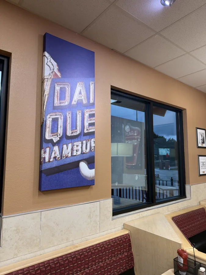 A painted panel of a vintage "Dairy Queen Hamburgers" roadside sign hangs beside the front windows.