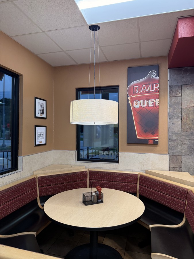 A curved red booth around a round table, with retro Dairy Queen sign art on the wall.