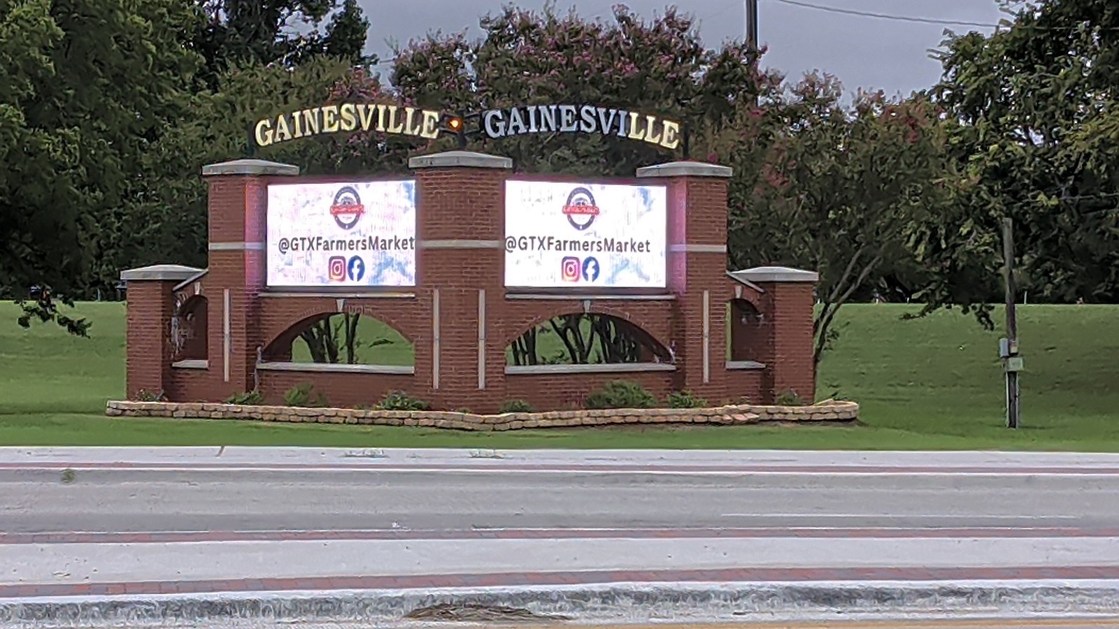The Gainesville marquee showing the @GTXFarmersMarket social handles, framed by crape myrtles.