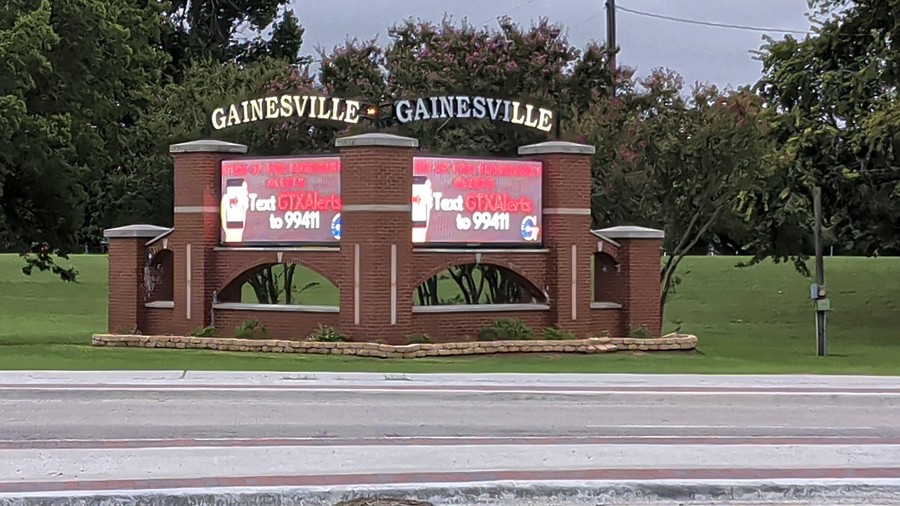 The twin screens of the Gainesville marquee glow red with a text-alert sign-up message.