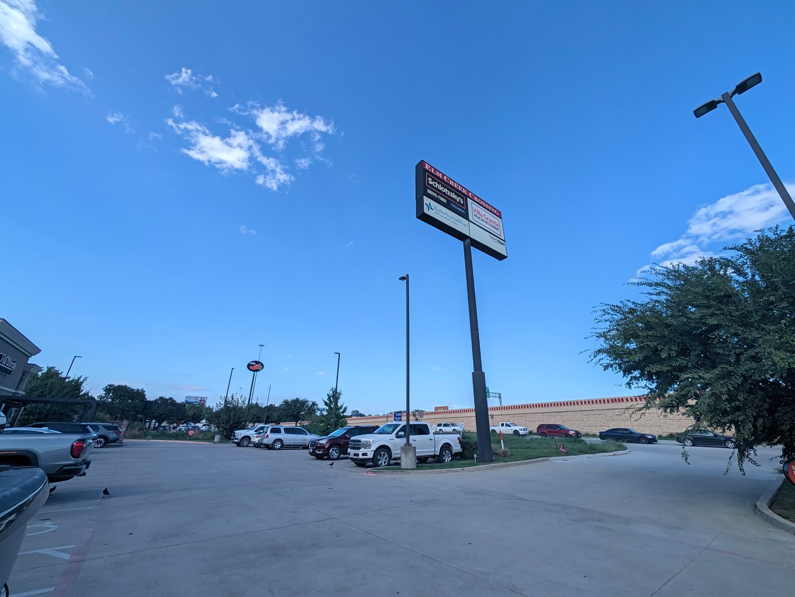 The Elm Creek Crossing sign lists Schlotzsky's and Cinnabon, Villa Grande Mexican Restaurant, Sport Clips and Baylor Scott & White Denton Heart Group.