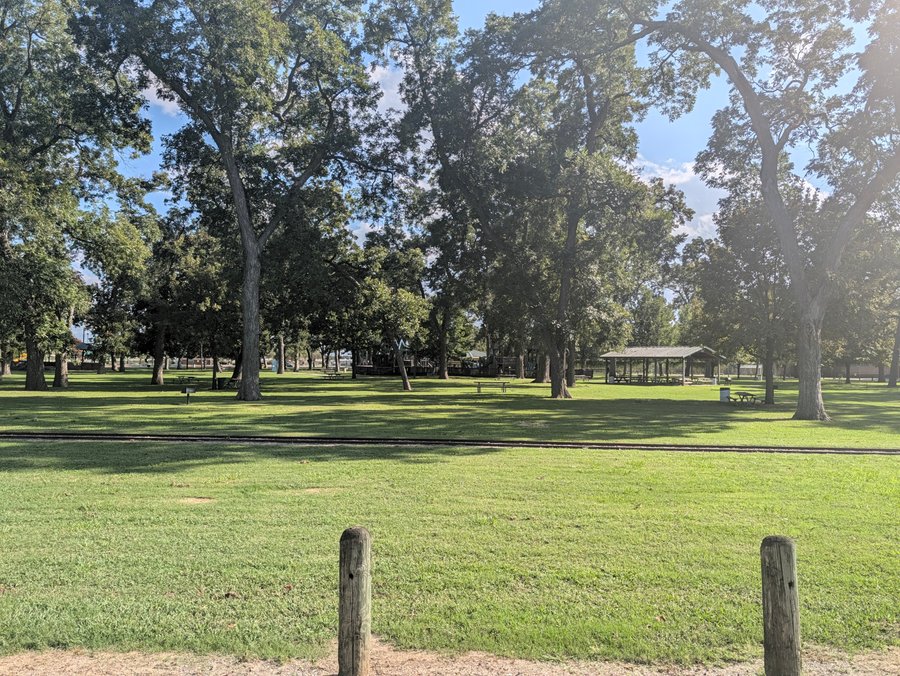 Tall trees shade the lawn and a picnic pavilion at Leonard Park on a clear October afternoon.
