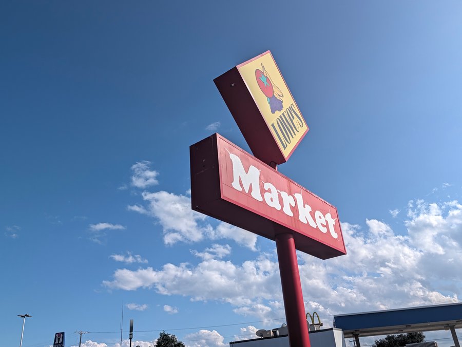The Lowe's Market sign rises against a blue sky on West California Street.