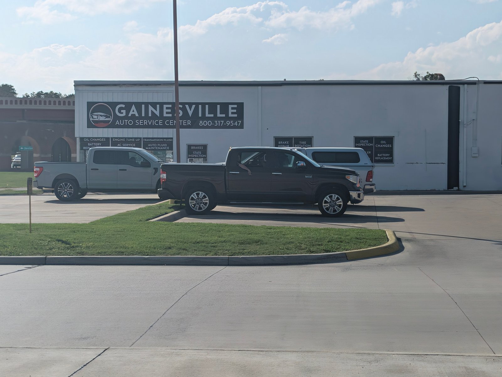 Pickups park outside Gainesville Auto Service Center, whose windows list oil changes, brakes and state inspections.