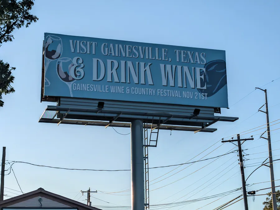 A billboard reads "Visit Gainesville, Texas & Drink Wine" and promotes the Gainesville Wine & Country Festival on Nov. 21.