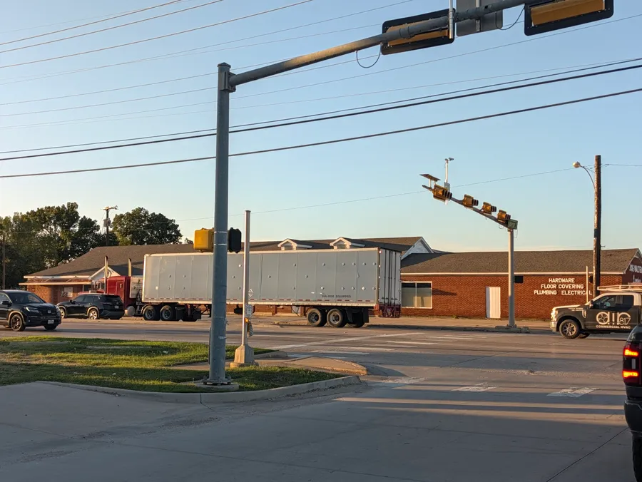 A truck passes Joe Walter Lumber, whose brick wall advertises hardware, floor covering, plumbing and electrical supplies.