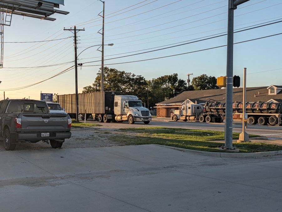 Eighteen-wheelers roll along US 82 at the Culberson Street signal in the early evening light.